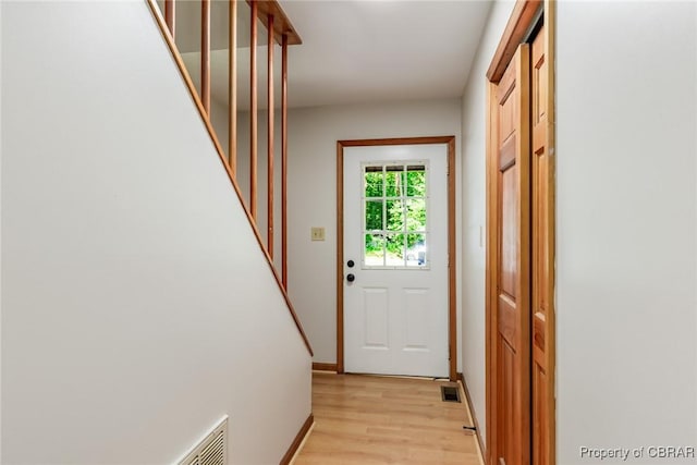 doorway to outside with light wood-style floors, visible vents, and baseboards