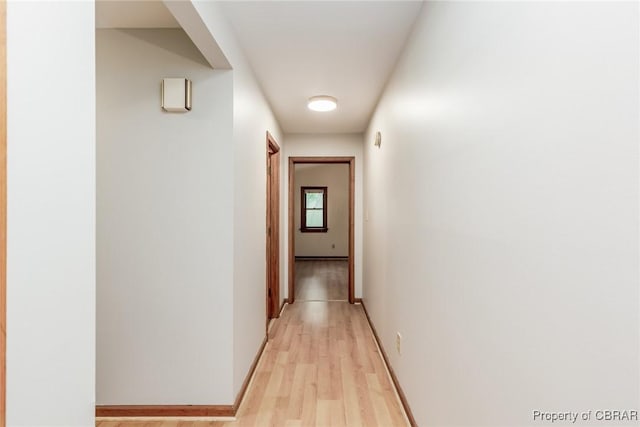 hall featuring light wood finished floors and baseboards