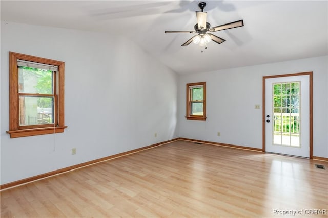 spare room featuring vaulted ceiling, light wood-style flooring, baseboards, and ceiling fan