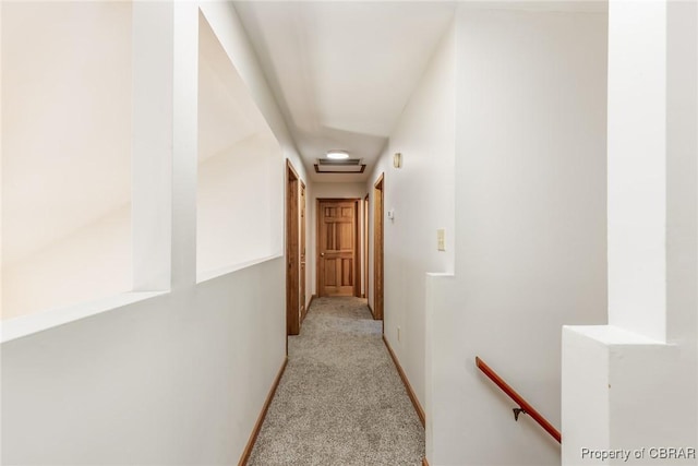 corridor with baseboards, light carpet, and an upstairs landing