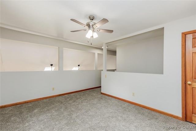 carpeted empty room with ceiling fan and baseboards