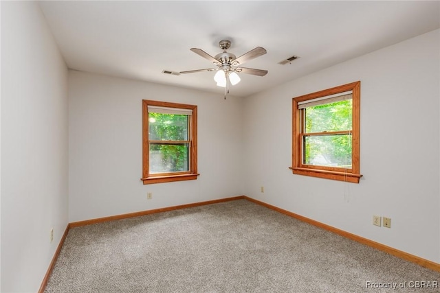 carpeted empty room featuring baseboards, visible vents, and ceiling fan