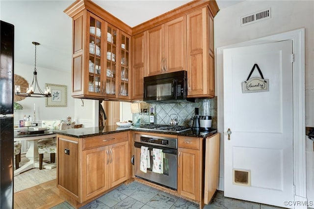 kitchen with appliances with stainless steel finishes, visible vents, dark stone countertops, and tasteful backsplash