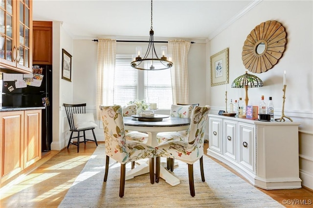 dining room featuring light wood finished floors, ornamental molding, and an inviting chandelier