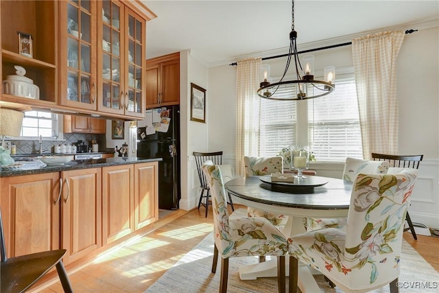 dining space featuring a notable chandelier, light wood-style flooring, a wealth of natural light, and crown molding