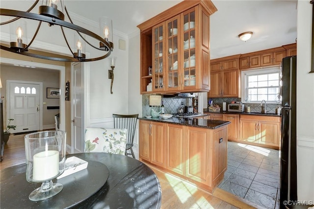 kitchen with a sink, ornamental molding, freestanding refrigerator, tasteful backsplash, and an inviting chandelier