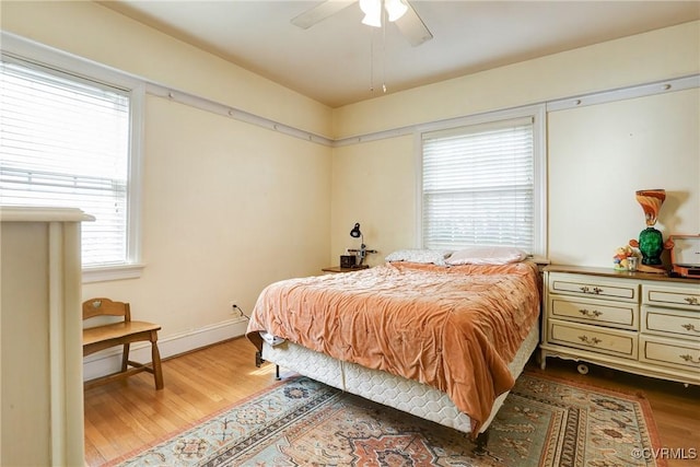 bedroom with ceiling fan, wood finished floors, and baseboards