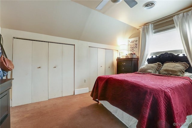 bedroom with carpet floors, two closets, visible vents, vaulted ceiling, and ceiling fan