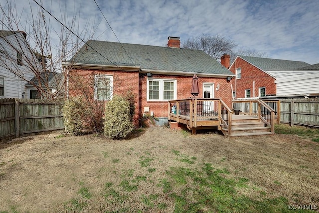 rear view of house featuring brick siding, a chimney, a lawn, a fenced backyard, and a wooden deck