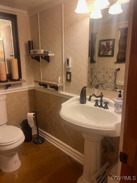 half bathroom with toilet, an inviting chandelier, and crown molding