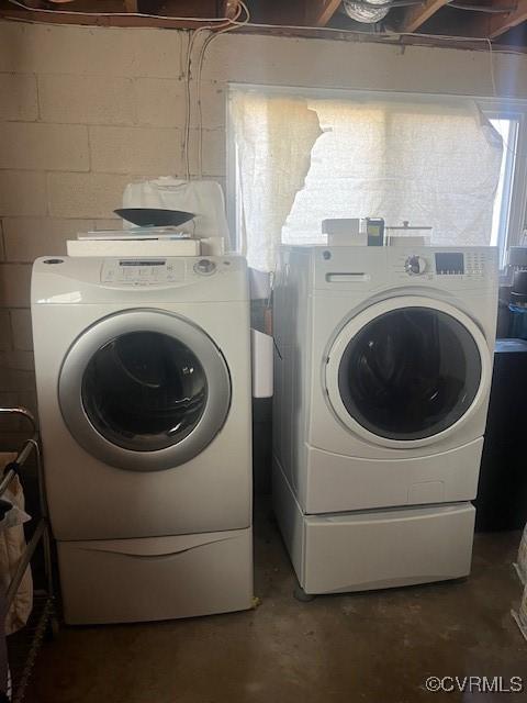 clothes washing area with washing machine and dryer, laundry area, and concrete block wall