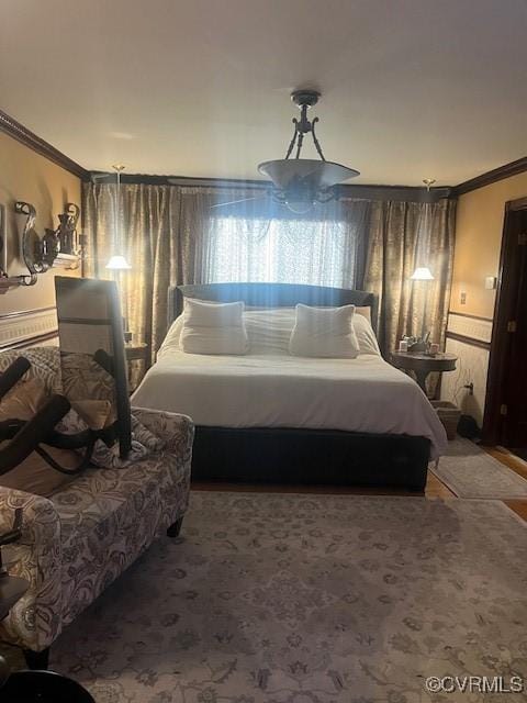 carpeted bedroom with ornamental molding and wainscoting