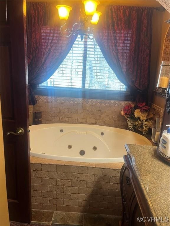 full bath featuring a healthy amount of sunlight, a tub with jets, and vanity