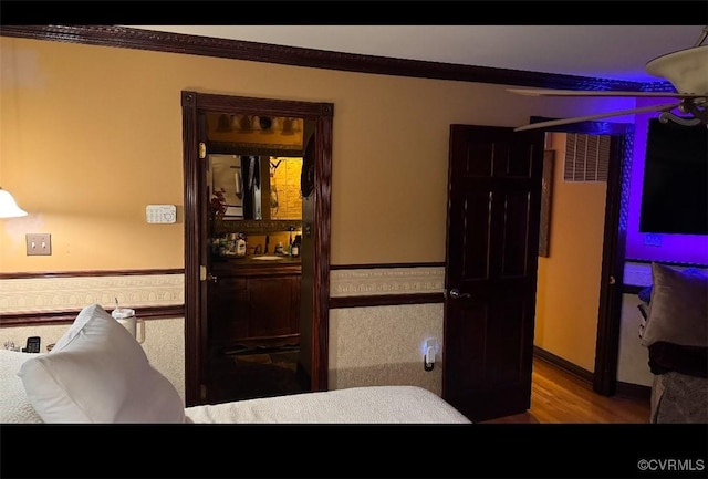 bedroom with wood finished floors and crown molding