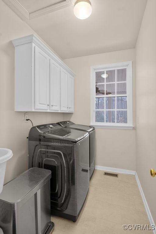 washroom with visible vents, cabinet space, washer and clothes dryer, and baseboards