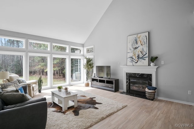 living area featuring high vaulted ceiling, wood finished floors, baseboards, and a premium fireplace