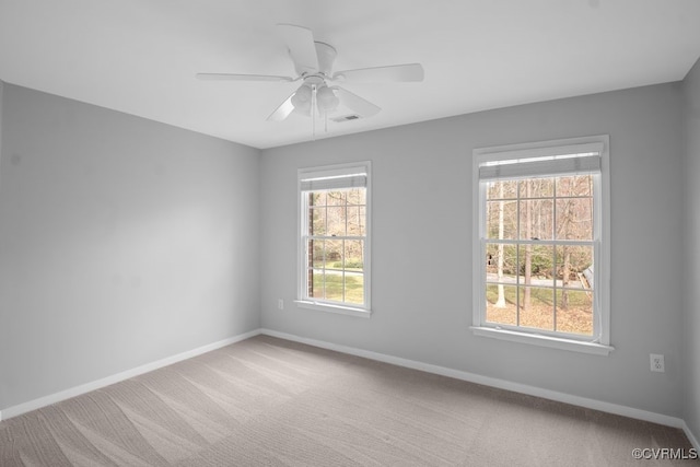 carpeted spare room featuring visible vents, ceiling fan, and baseboards