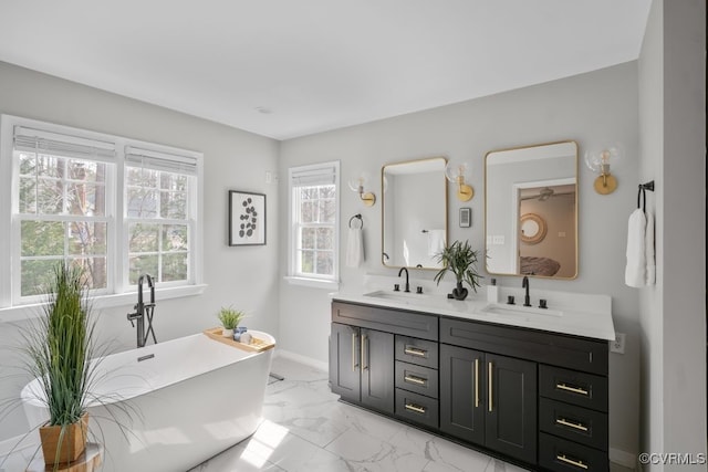 bathroom with marble finish floor, double vanity, a soaking tub, and a sink