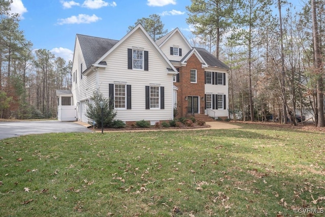 view of front of home with a front yard, brick siding, and driveway