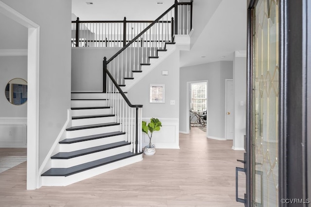 foyer featuring stairs, ornamental molding, a high ceiling, and wood finished floors