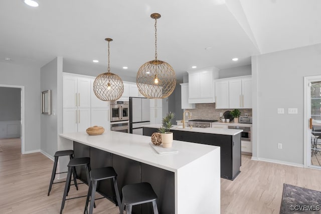 kitchen with light wood-type flooring, a large island, white cabinetry, and decorative backsplash