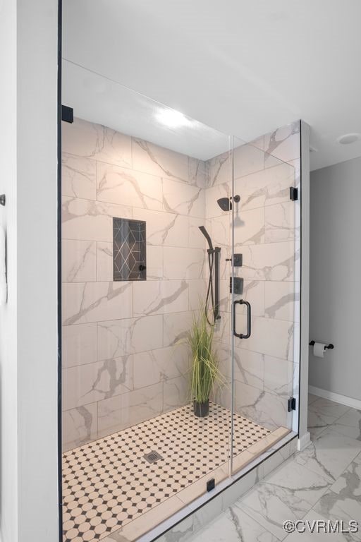 bathroom with a stall shower, baseboards, and marble finish floor