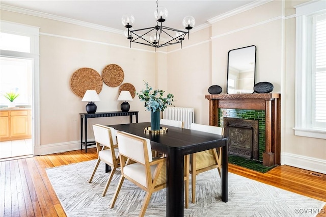 dining space featuring light wood-type flooring, radiator heating unit, visible vents, and ornamental molding