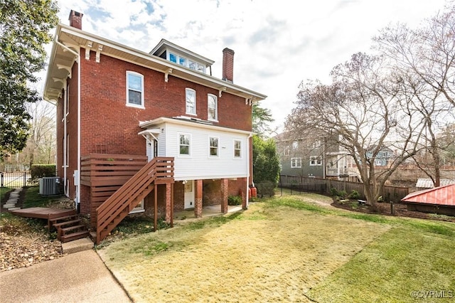 rear view of property with central air condition unit, a chimney, and brick siding