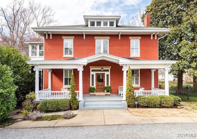 view of front of home featuring covered porch, brick siding, and fence