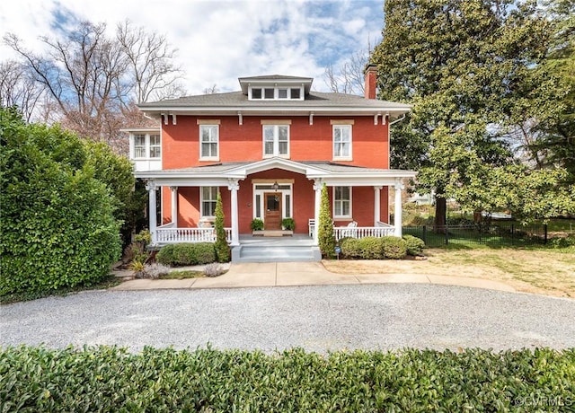 american foursquare style home with a porch, fence, and a chimney