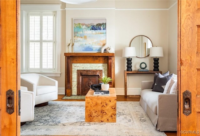 sitting room featuring a fireplace with flush hearth, crown molding, baseboards, and wood finished floors