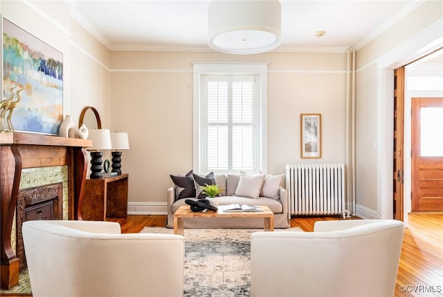 living area with plenty of natural light, radiator heating unit, a fireplace, and wood finished floors