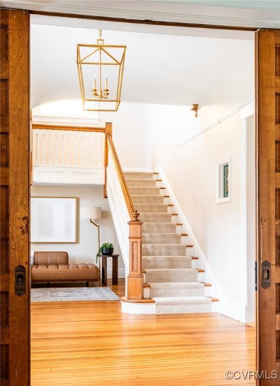 staircase featuring wood finished floors and an inviting chandelier