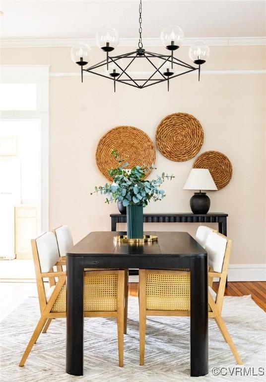 dining room with ornamental molding, wood finished floors, baseboards, and an inviting chandelier