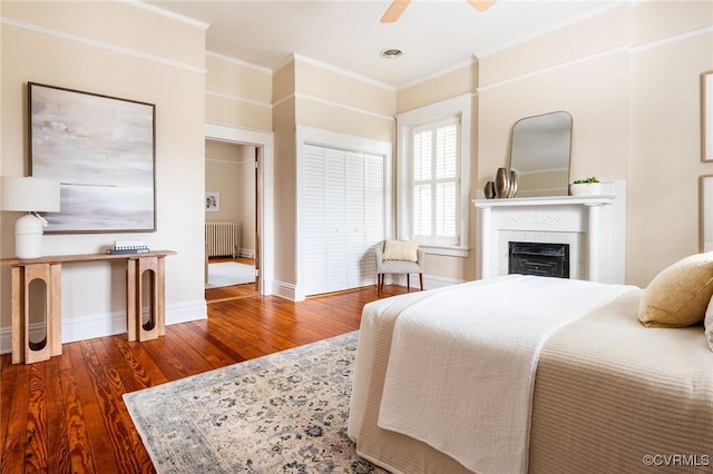 bedroom with crown molding, wood finished floors, visible vents, and radiator