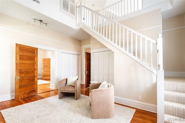 sitting room featuring stairs, baseboards, and wood finished floors