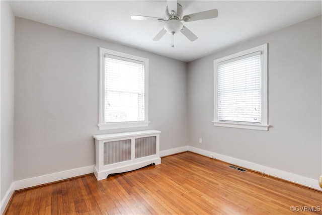 spare room with plenty of natural light, radiator, baseboards, and light wood-style floors