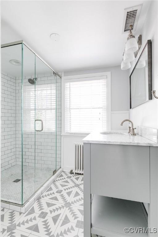 full bath with vanity, radiator, visible vents, and a stall shower