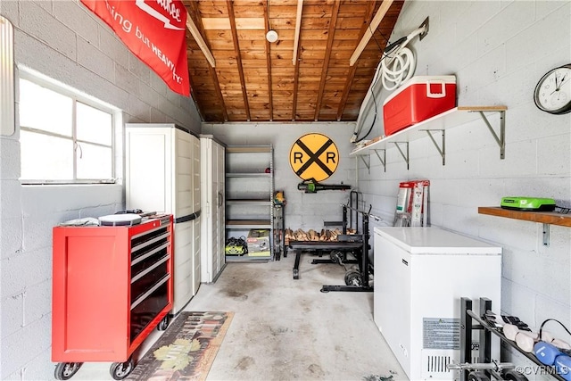 garage featuring fridge, concrete block wall, and wooden ceiling