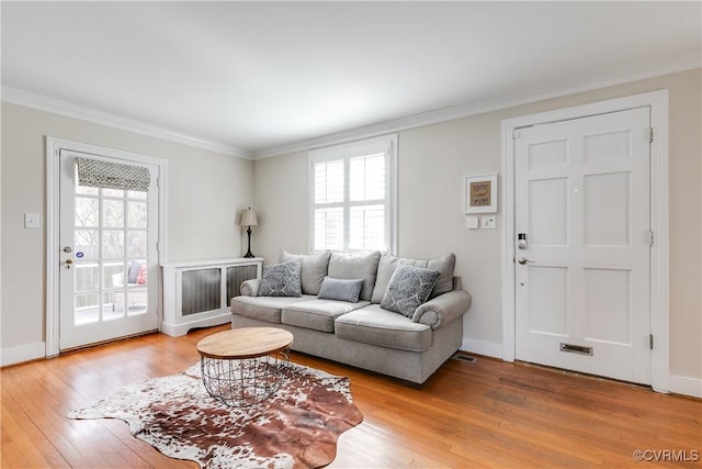 living room with light wood-style flooring, baseboards, and ornamental molding