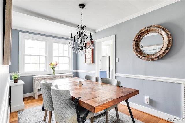 dining area featuring light wood-type flooring, crown molding, and baseboards