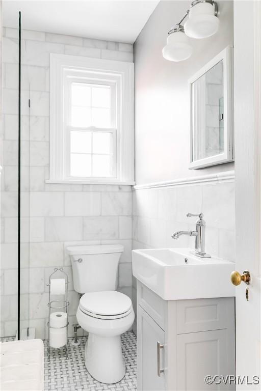 bathroom featuring vanity, tile walls, and toilet