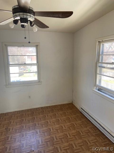 empty room with a baseboard heating unit, vaulted ceiling, a wealth of natural light, and a ceiling fan