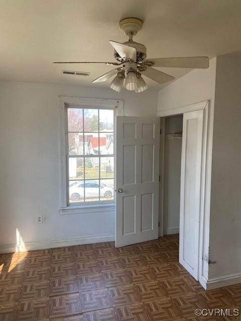 interior space featuring a ceiling fan, visible vents, and baseboards