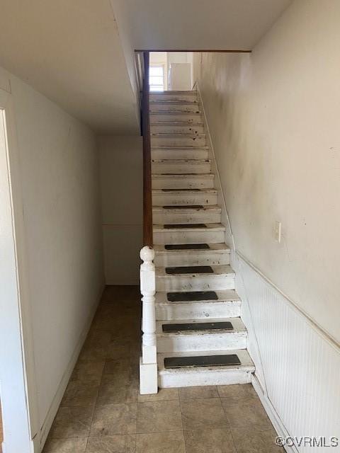 stairs featuring a wainscoted wall