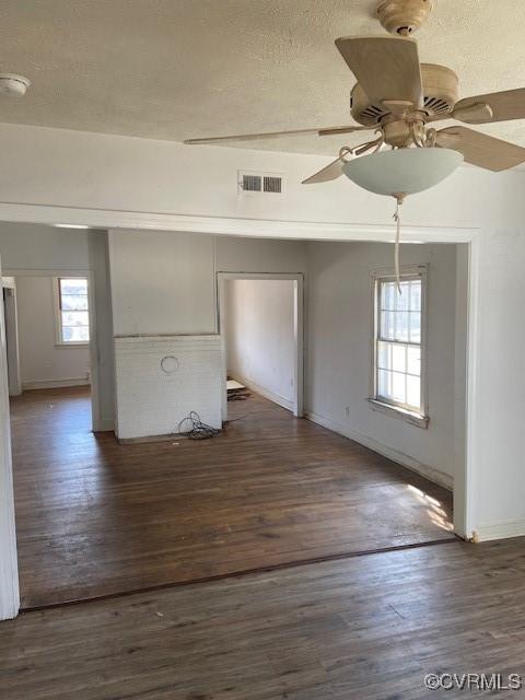 unfurnished room with visible vents, baseboards, dark wood-style floors, ceiling fan, and a textured ceiling