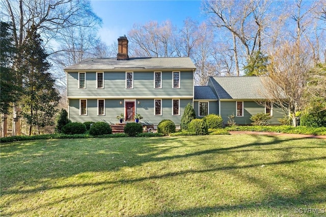 colonial house featuring a chimney and a front lawn