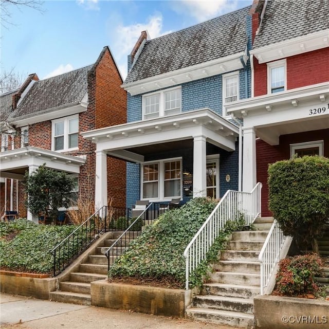 view of front of property featuring brick siding, a high end roof, mansard roof, and a porch