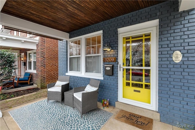 doorway to property with a porch and brick siding