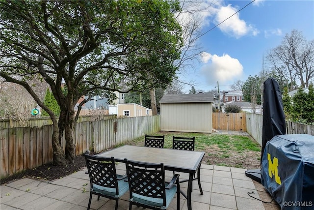 view of patio featuring outdoor dining area, a fenced backyard, a storage shed, an outdoor structure, and a grill